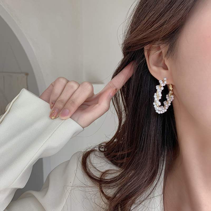 Close-up detail of lustrous pearl embellishment on polished gold round hoop design