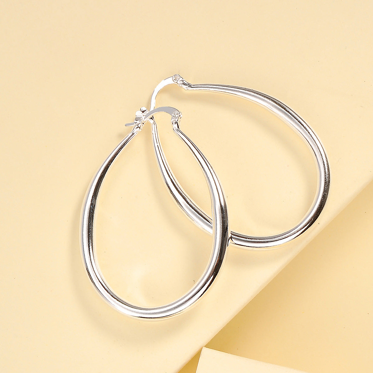 Close-up view of oval gold earring showing detailed geometric design and metallic sheen