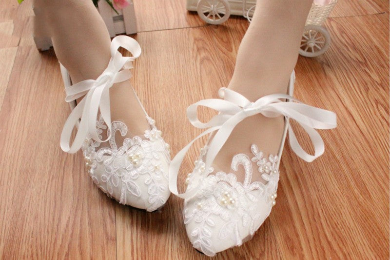 Close-up of intricate white lace embroidery and beading on wedding shoe