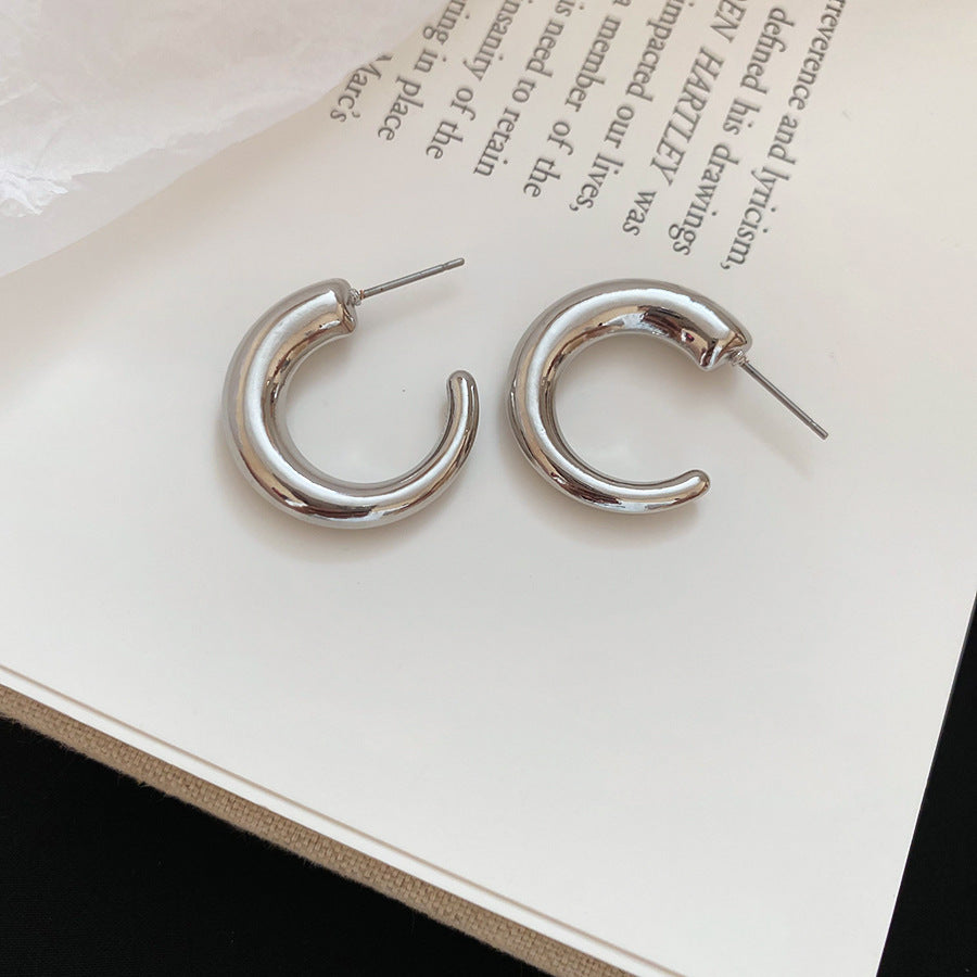 Overhead flat lay of silver hoop earrings on neutral background