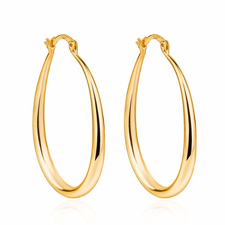 Pair of gold geometric oval earrings displayed together on neutral surface