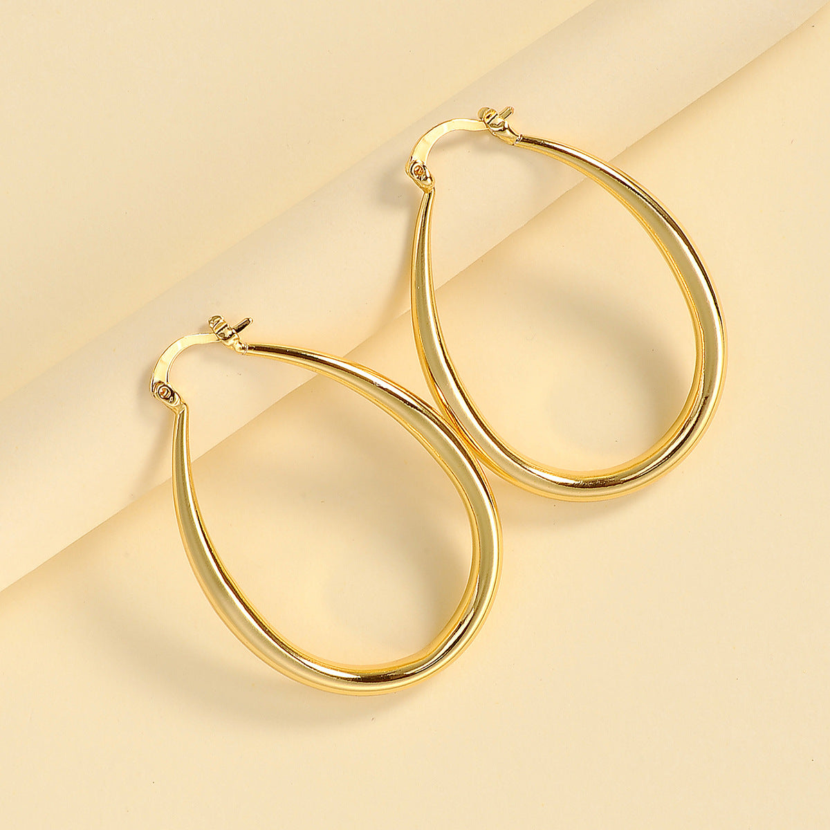 Gold oval earring worn on ear, demonstrating how accessory sits and catches light