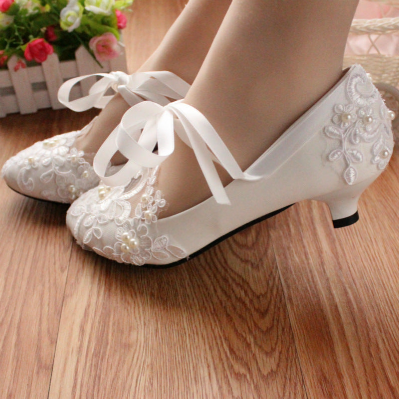 Side profile view of white lace bridal shoe showing heel height and curve