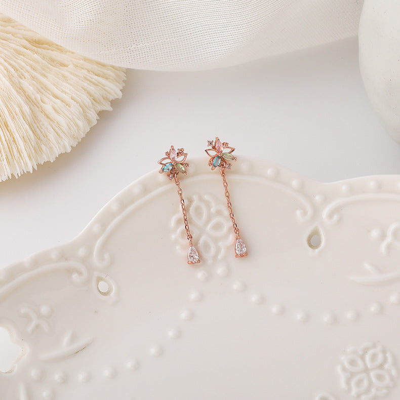 Close-up detail of intricate flower design and shimmering tassel embellishment on earrings