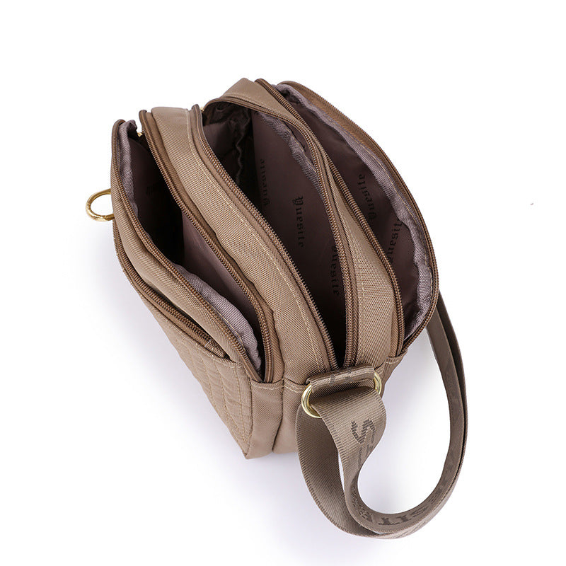Front view of black crossbody bag showing quilted leather texture and gold hardware
